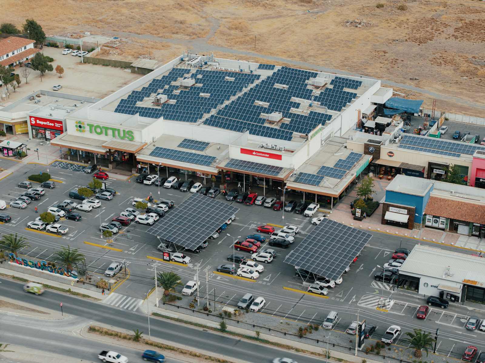 Vista aérea del centro comercial Paseo Parque Machalí con paneles solares sobre la cubierta del Tottus y dos estacionamientos solares en el aparcamiento